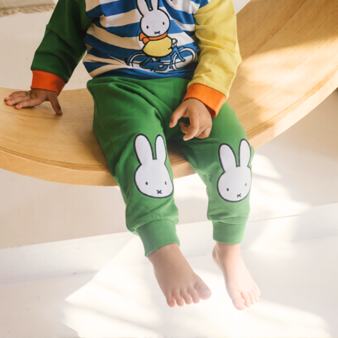 Child wearing the Miffy on the Move bamboo lounge set with bicycle sweatshirt and green joggers