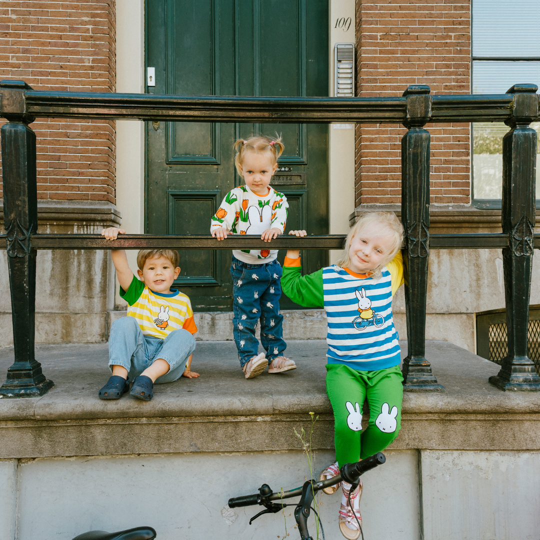 Child wearing the Miffy on the Move bamboo lounge set with bicycle sweatshirt and green joggers